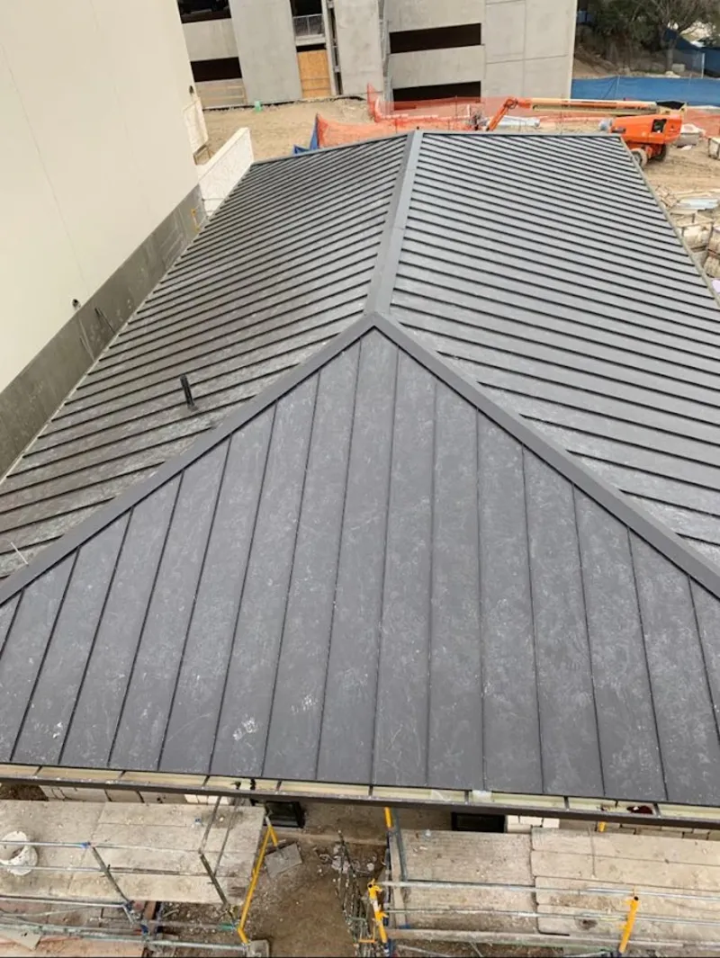 Commercial metal roof construction with crane equipment in Foley